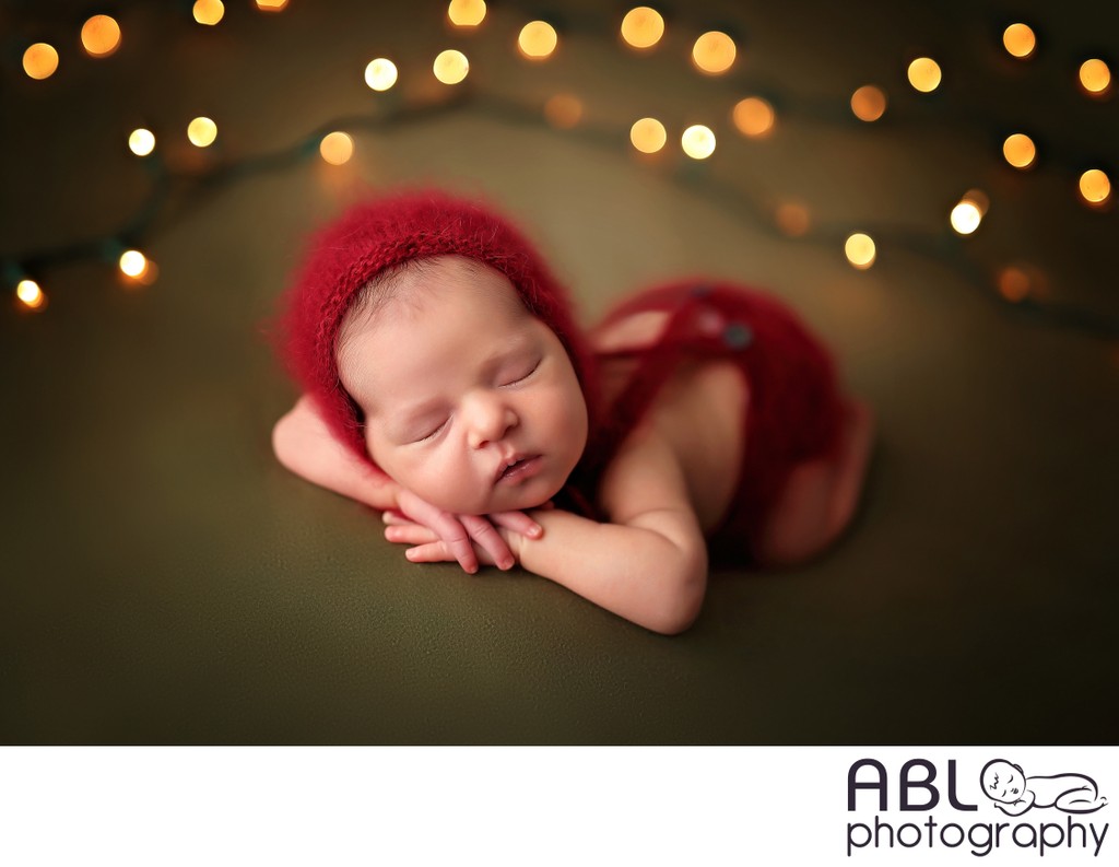 Newborn in red outfit on green background with lights