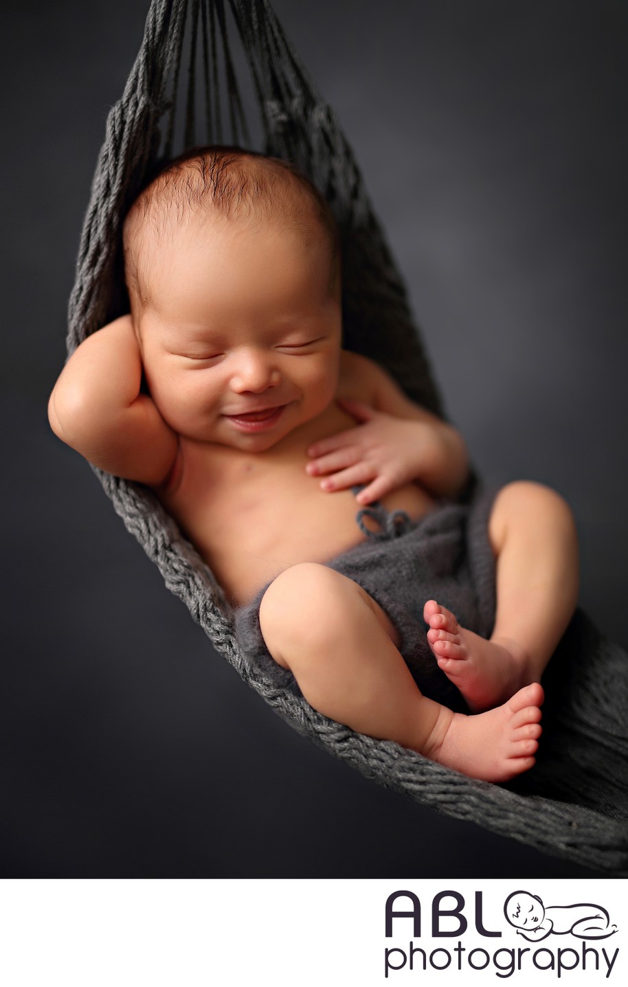 Baby boy smiling in a gray hammock