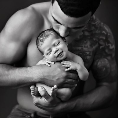 Father holding newborn baby skin to skin