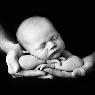 Black and white hands holding newborn