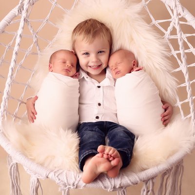 Pictures of big brother with newborn twins in San Diego