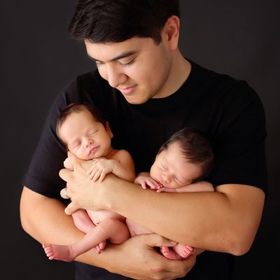 Dad holding twins in San Diego newborn photo studio