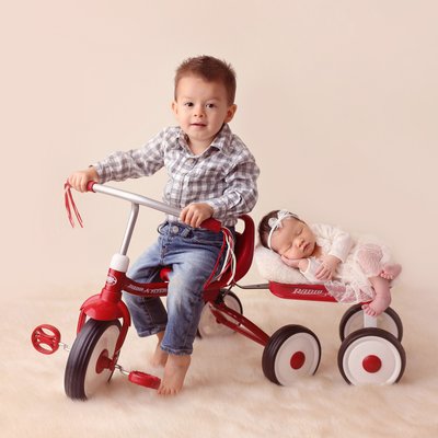 Older brother riding a bike with baby sister, newborn photos