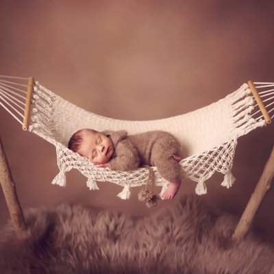 Baby in cream hammock on brown background
