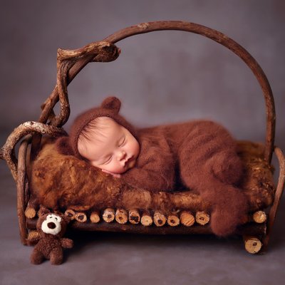 baby boy in bear outfit on wooden bed