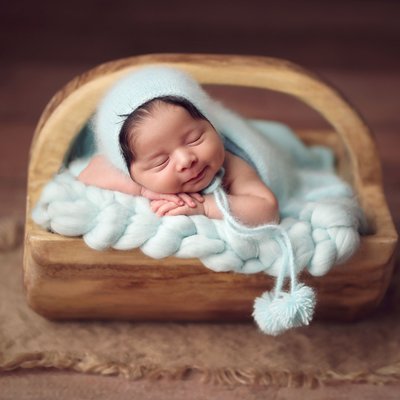smiling baby boy in wooden bucket