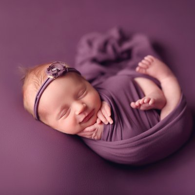 Smiling baby girl wrapped in purple