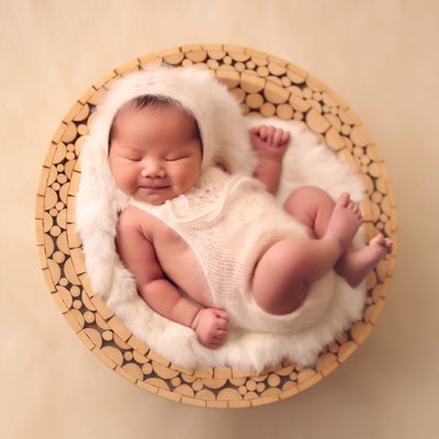 baby girl smiling in round wooden bowl