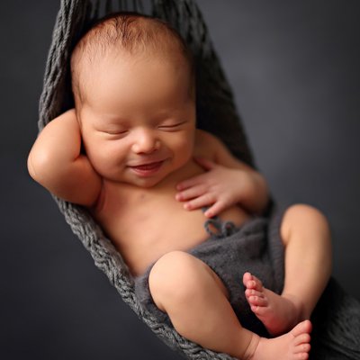 Baby boy smiling in a gray hammock