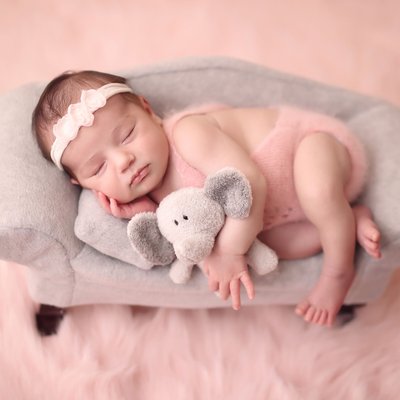 baby in pink outfit on gray couch