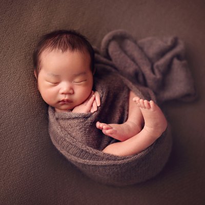 wrapped baby on brown blanket