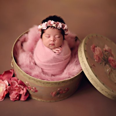 newborn girl wrapped in round box