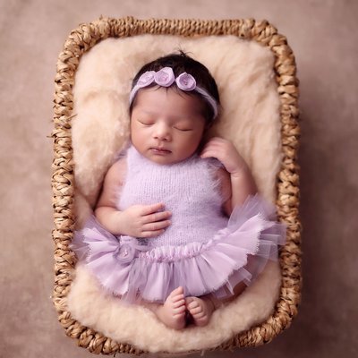 newborn baby asleep in lavender dress in box