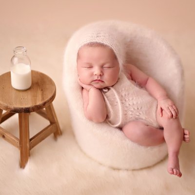 Baby in cream chair with milk bottle