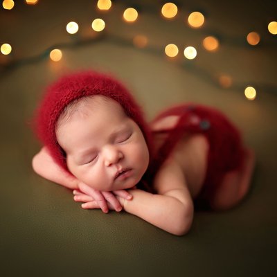 Newborn in red outfit on green background with lights