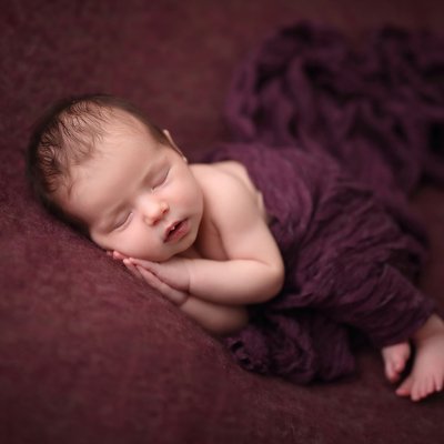 baby posed on purple blanket