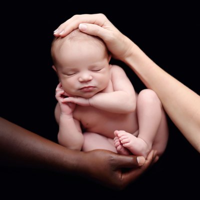 multiracial parents hands holding baby