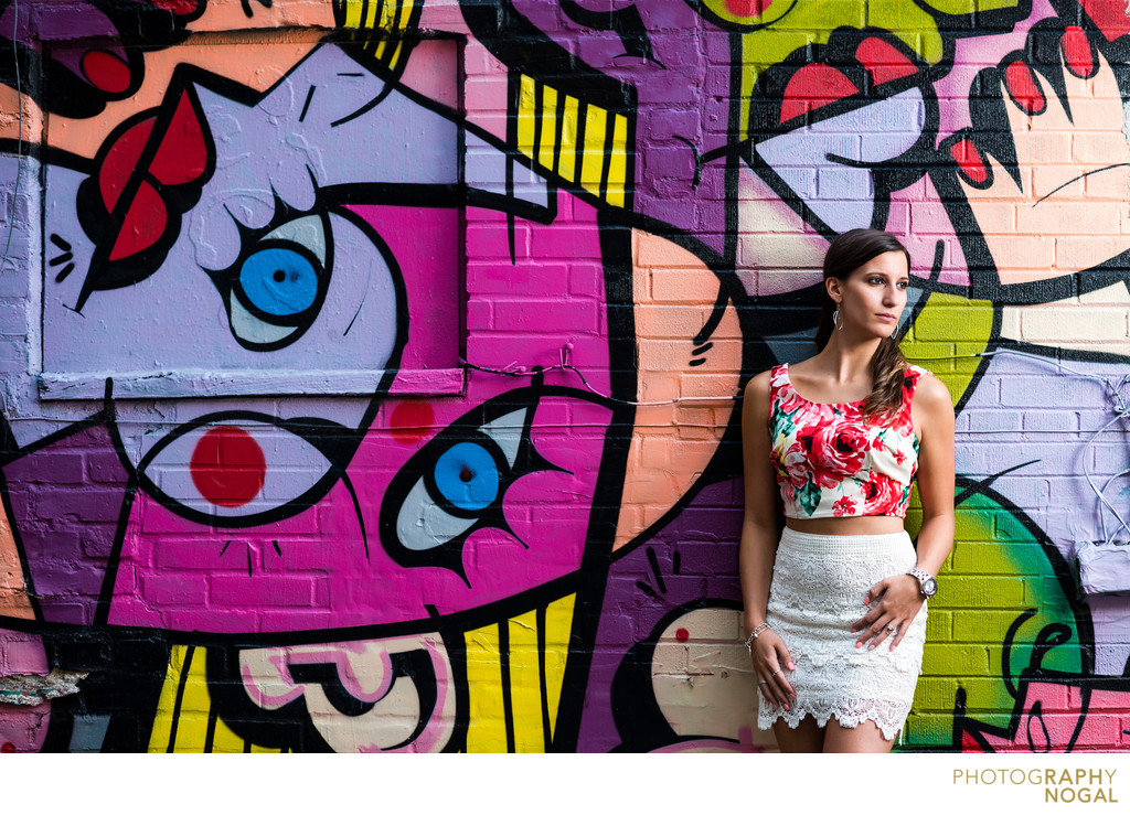 Toronto woman in floral top poses against graffiti wall