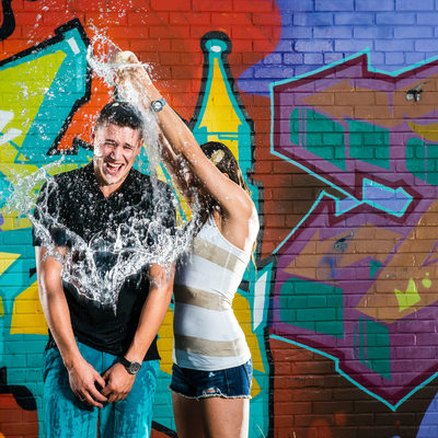 couples splash each other with water during engagement