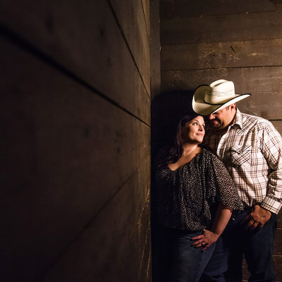 Cowboy couple in a horse stable during engagement shoot