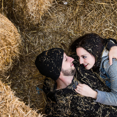 Couple snuggling within the haybale pile 