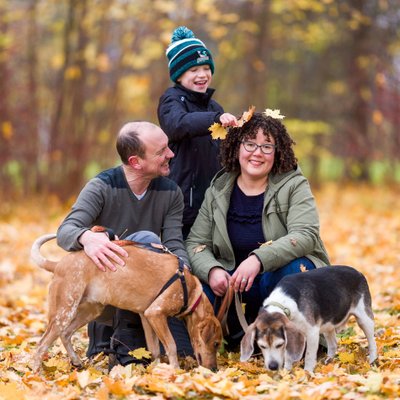 kid putting leaves on mom's head during fall portraits