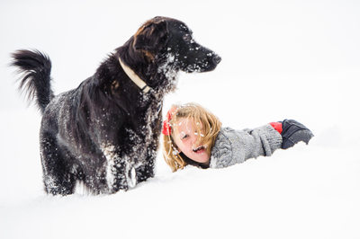 girl playing with dog in the snow