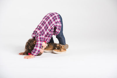 A kid doing the downward dog in the studio