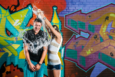 couples splash each other with water during engagement