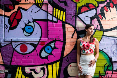 Toronto woman in floral top poses against graffiti wall