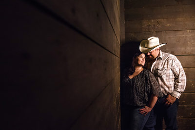 Cowboy couple in a horse stable during engagement shoot