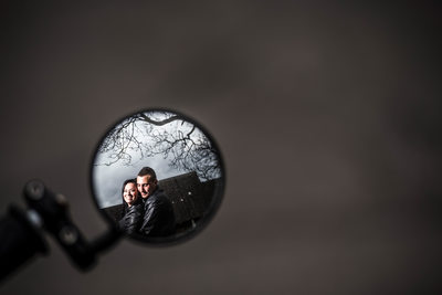 A couple wearing leather jackets hugging in reflection