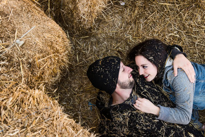 Couple snuggling within the haybale pile 