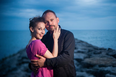 Couple at edge of rock peer at dusk.