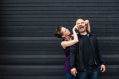 Toronto couple goofs around in front of black backdrop