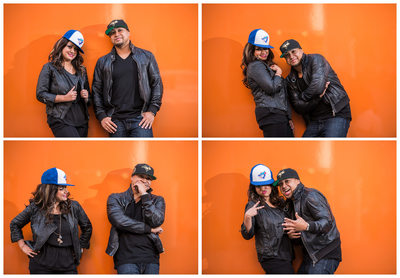 Couple lets loose in sports hats against orange wall