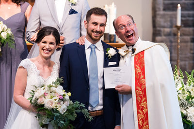 Priest Posing for Photo with Couple 