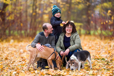 kid putting leaves on mom's head during fall portraits