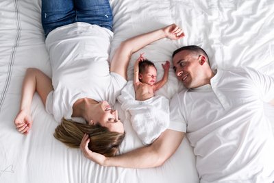 family with newborn baby lying on the bed