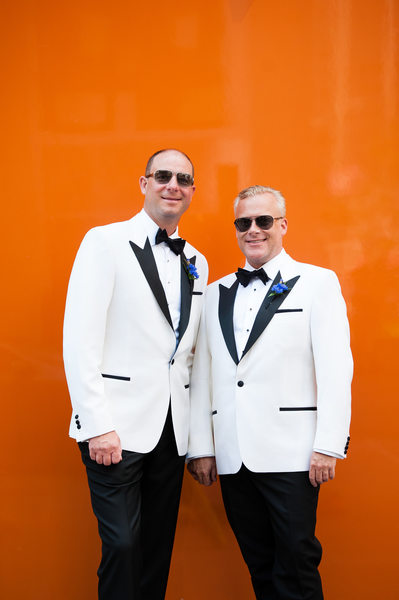 Same Sex Couple Looking Sharp by an Orange Wall