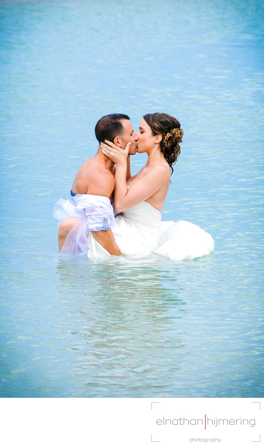 bride and groom kissing in water
