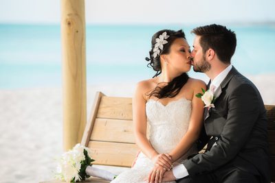 bench kissing bride groom beach