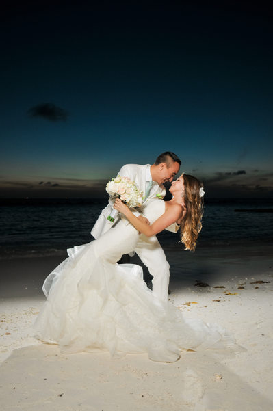 groom dipping bride on beach