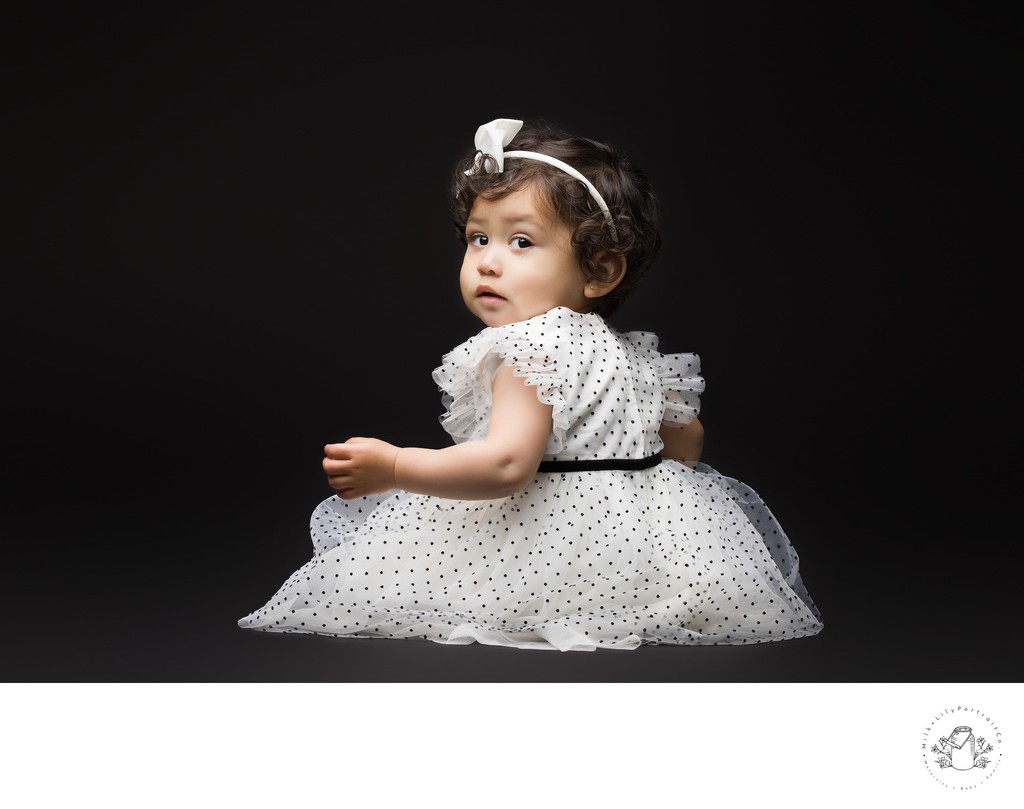 Striking baby portrait against a black background, highlighting the baby's pure innocence and expression.