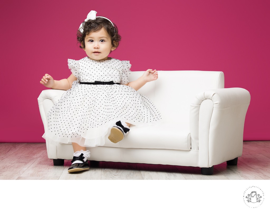 baby in white dress on a small couch