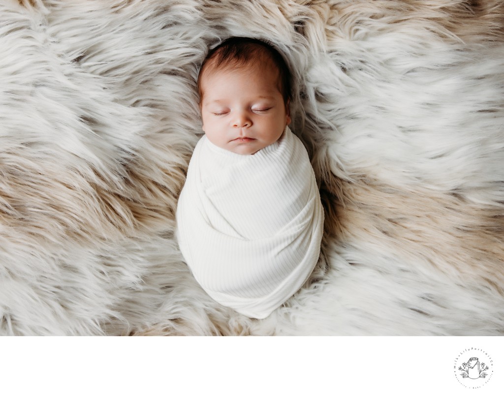 Swaddled newborn sleeping on fuzzy blanket session