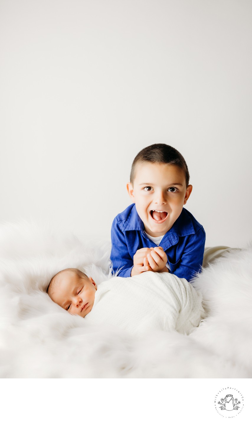 newborn and brother portrait session white backdrop