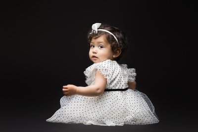 Striking baby portrait against a black background, highlighting the baby's pure innocence and expression.