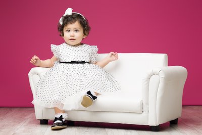 baby in white dress on a small couch