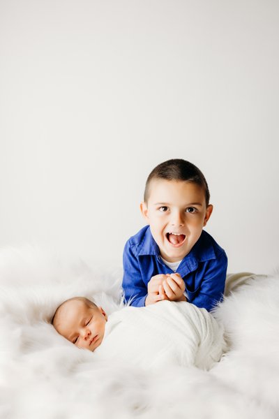 newborn and brother portrait session white backdrop